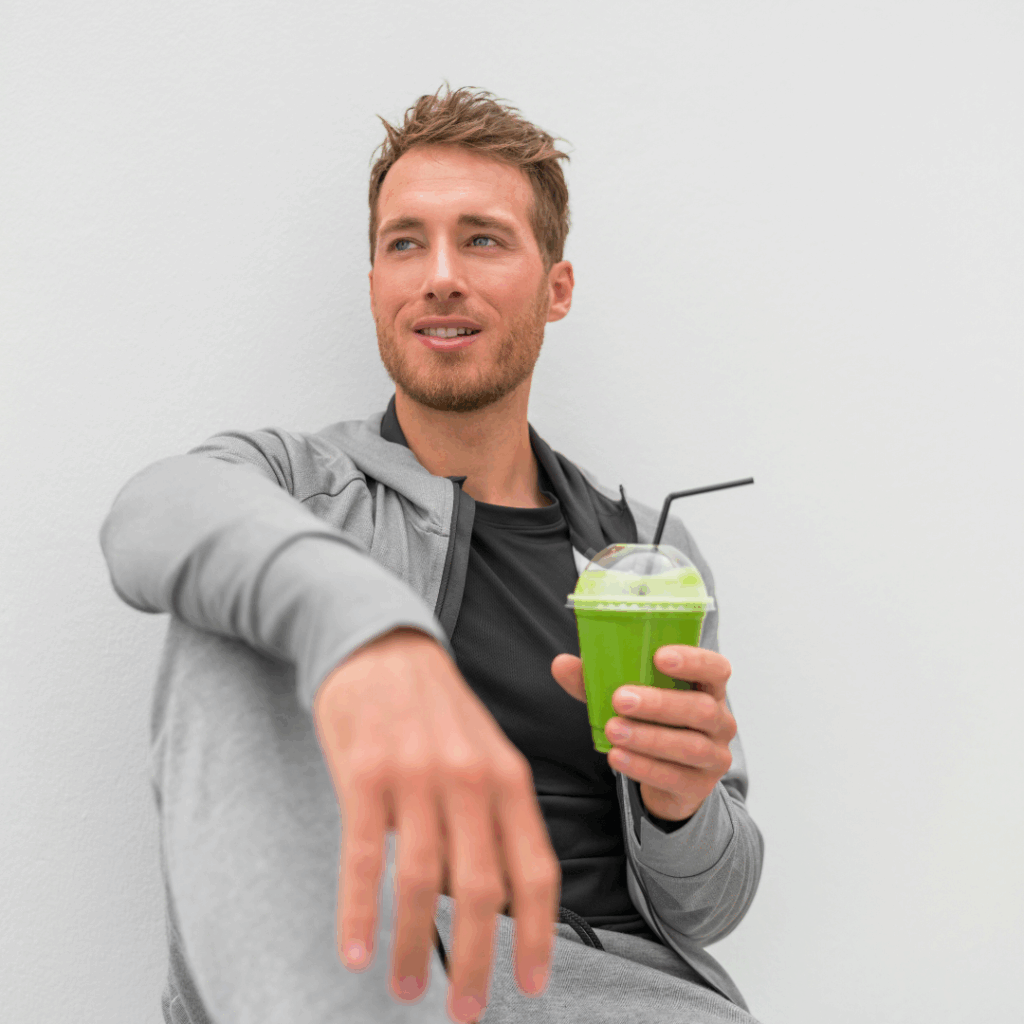Muškarac u sportskoj odjeći odmara nakon treninga i drži zeleni Herbalife shake, uživajući u zdravom napitku koji podržava njegovu energiju i oporavak.