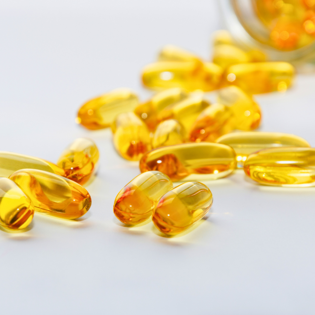 Žute kapsule omega-3 masnih kiselina razasute po bijeloj podlozi, simboliziraju prirodnu podršku zdravlju srca i snižavanju kolesterola uz dodatke prehrani poput Forever Arctic Sea.