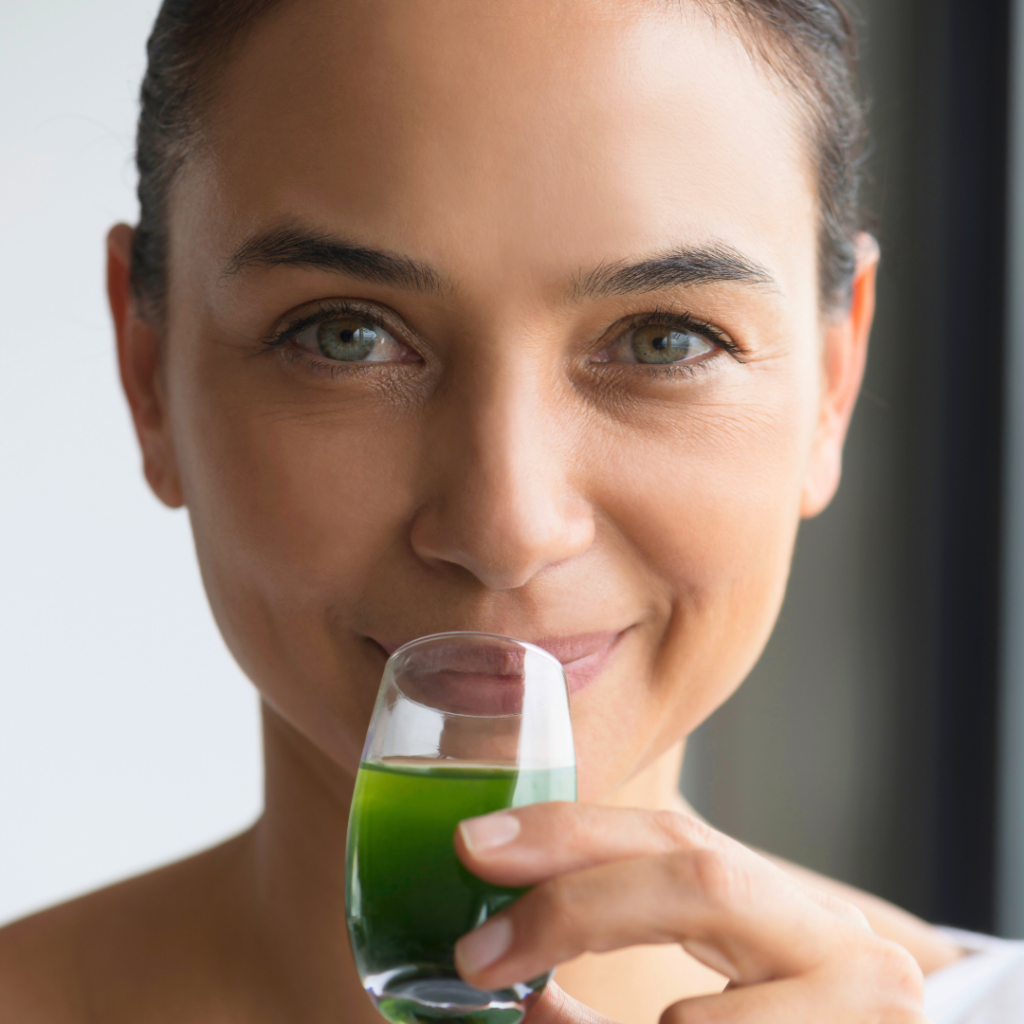 Čaša zelenog napitka u rukama žene simbolizira moć zelenih biljaka – kao što su spirulina, alfalfa i ječmena trava – koje se nalaze u kapsulama Forever Fields of Greens.