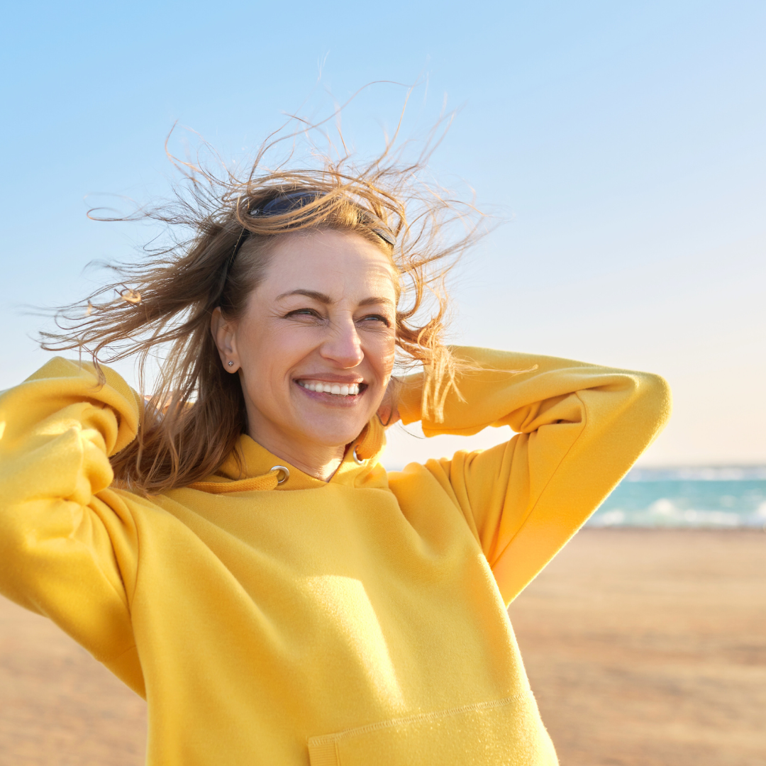 Našmijana žena u žutom puloveru simbolizira ravnotežu hormona i samopouzdanje koje dolazi kada žena upozna i razumije svoje tijelo.