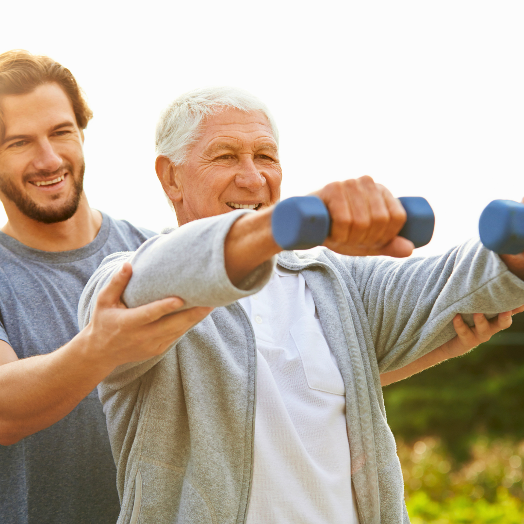 Stariji muškarac vježba s bučicama uz nadzor trenera, pokazujući kako redovita tjelovježba usporava biološko starenje i čuva snagu mišića u starijoj dobi.