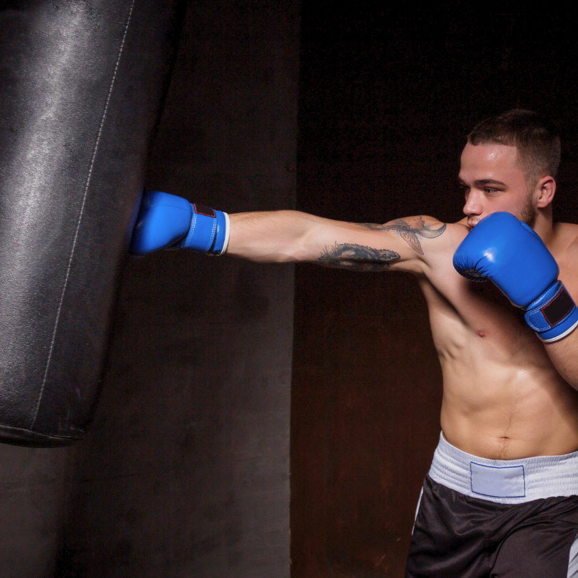 Muškarac izvodi snažan direkt udarac na boksačkoj vreći – boks fitness kao učinkovit način za izbacivanje stresa i poboljšanje kondicije.