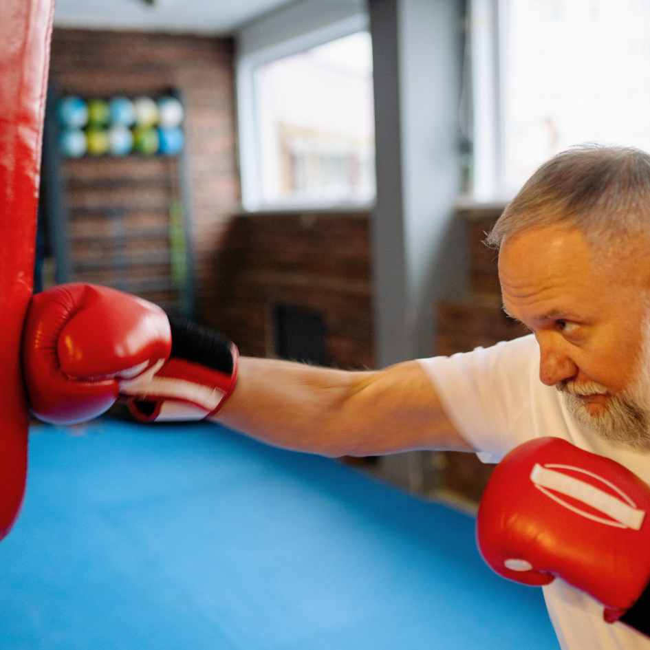 Muškarac u srednjim godinama udara boksačku vreću – boks fitness trening za izbacivanje stresa i očuvanje kondicije nakon 30.