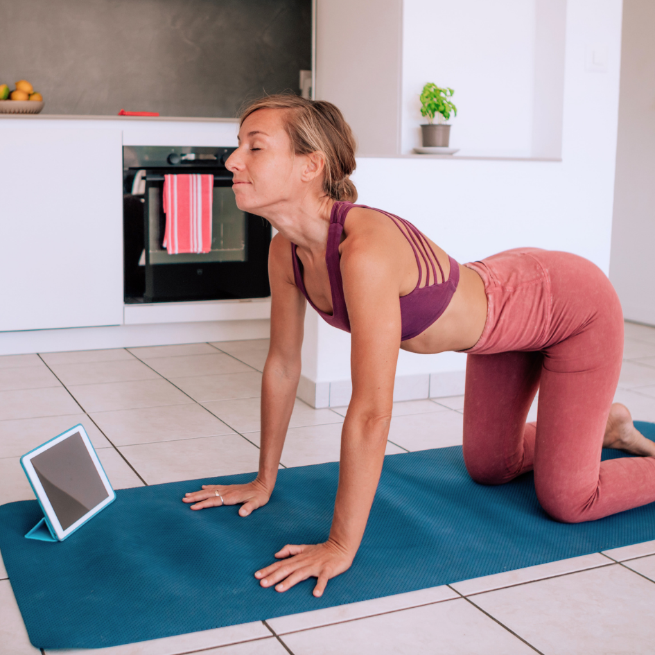 Žena trenira kod kuće na prostirci uz tablet – kratki, fokusirani trening u vlastitom prostoru bez gužve i gubljenja vremena.