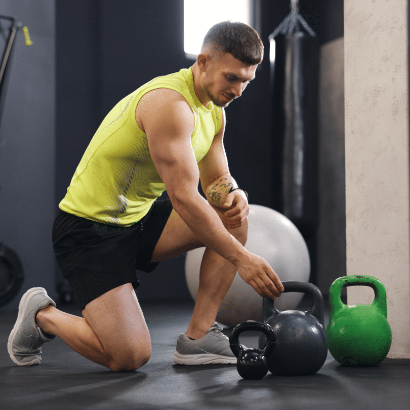 Muškarac priprema funkcionalni trening s girjama u teretani, kombinirajući rad na snazi, stabilnosti i kondiciji, što potvrđuje da učinkovit trening za muškarce ne znači samo dizanje utega već i razvoj pokretljivosti, kontrole tijela i funkcionalne izdržljivosti.