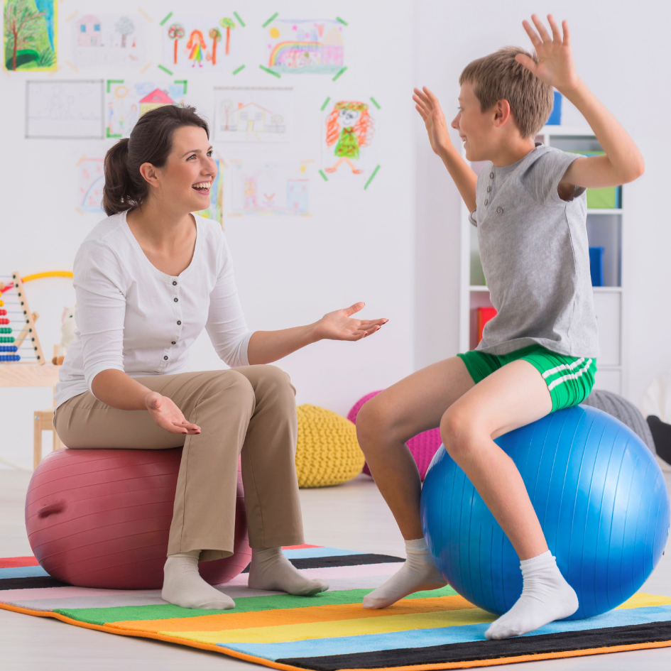 Fizioterapeut radi vježbe s djetetom na pilates lopti, što prikazuje važnost ciljane tjelovježbe, stručnog vodstva i redovitog kretanja u prevenciji bolova u donjem dijelu leđa te poboljšanju držanja i stabilnosti tijela.