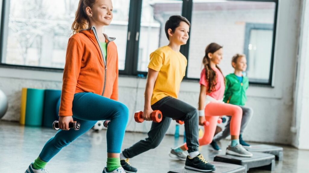 Djeca izvode iskorake s bučicama u teretani – trening snage prilagođen djeci